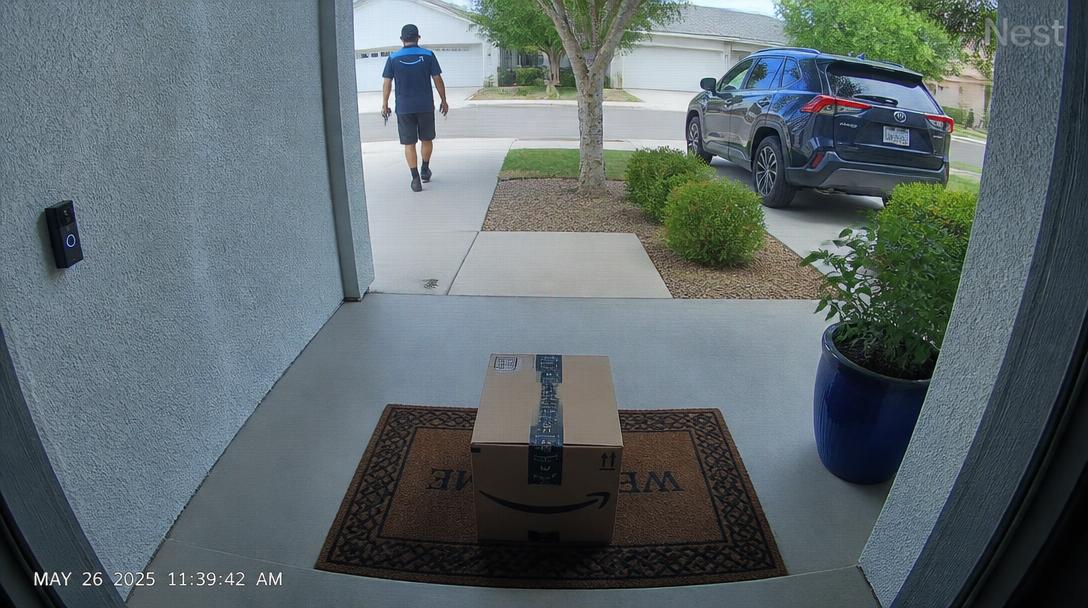 Front porch camera capture showing package delivered with driver still on-frame